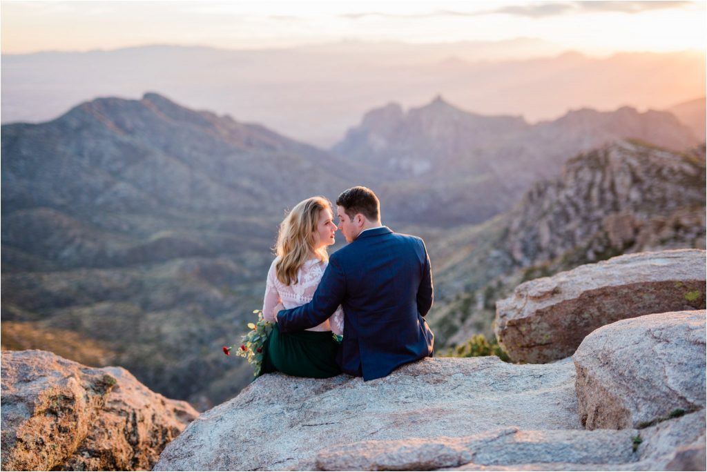 Man and woman sitting on a cliff at sunset
